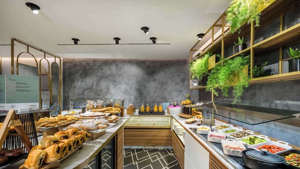 Una moderna disposición de buffet con diversos alimentos, una barra de madera y un arreglo de plantas en la pared.