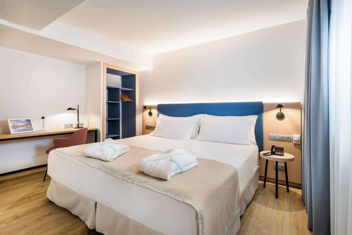 Une chambre d’hôtel avec un grand lit, des tables de chevet, un bureau et une armoire.