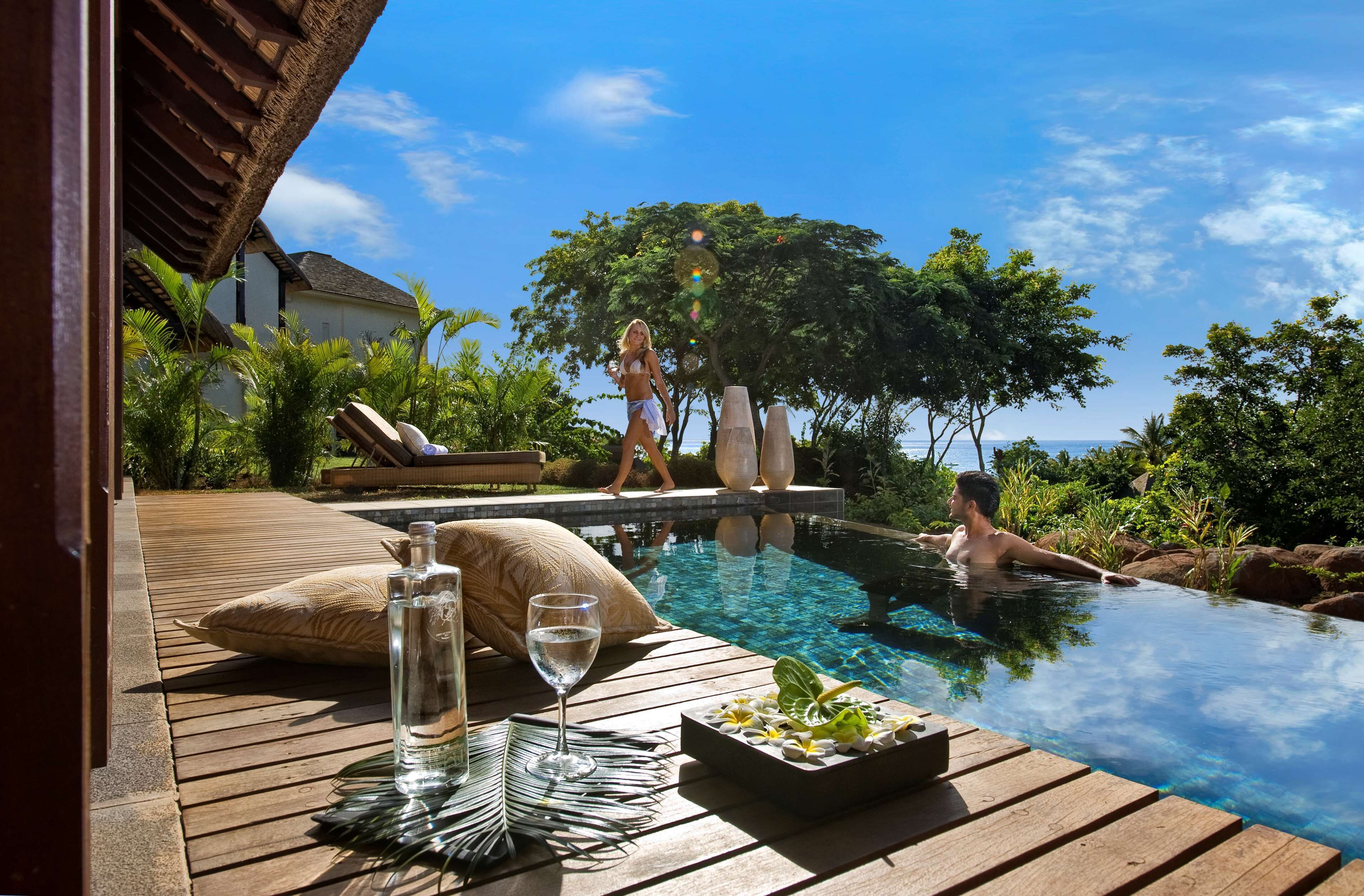 A wooden deck with a glass table, a bottle of water, and a glass of water.
