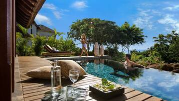 A wooden deck with a glass table, a bottle of water, and a glass of water.