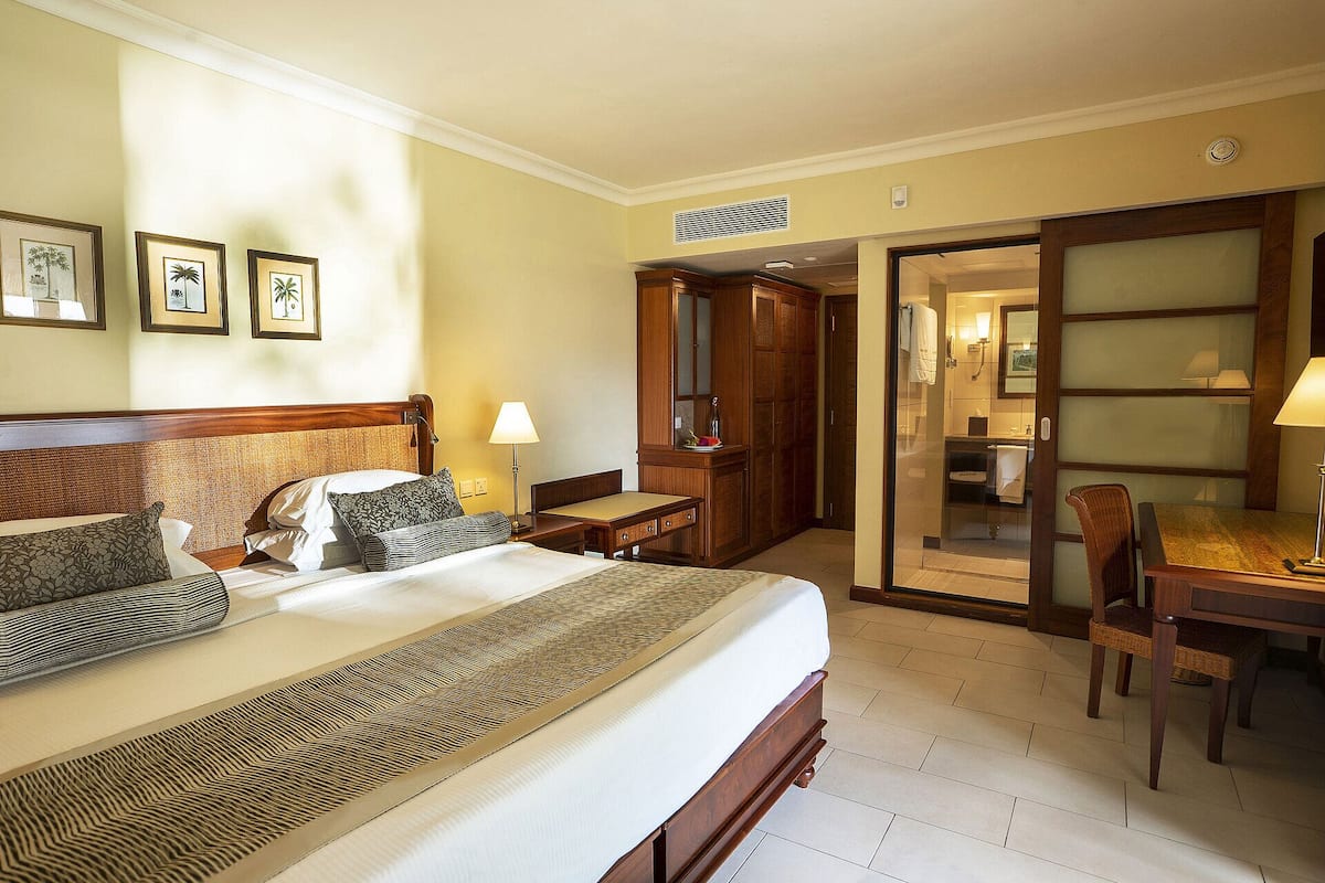 Ein Hotelzimmer mit einem großen Bett, einem Schreibtisch, einem Stuhl und einem durch eine offene Tür einsehbaren Badezimmer.