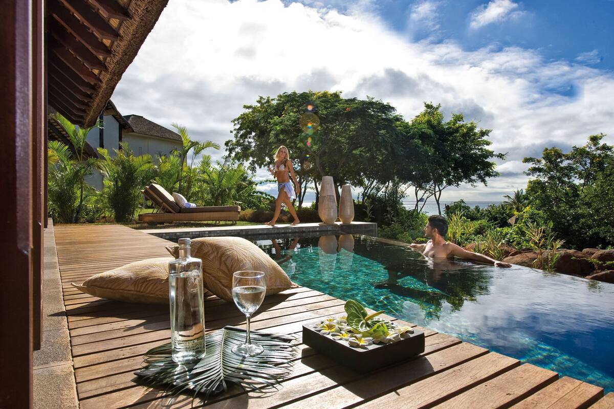 Ein Poolbereich mit Holzterrasse, Liegestühlen und freiem Blick auf das Schwimmbecken.