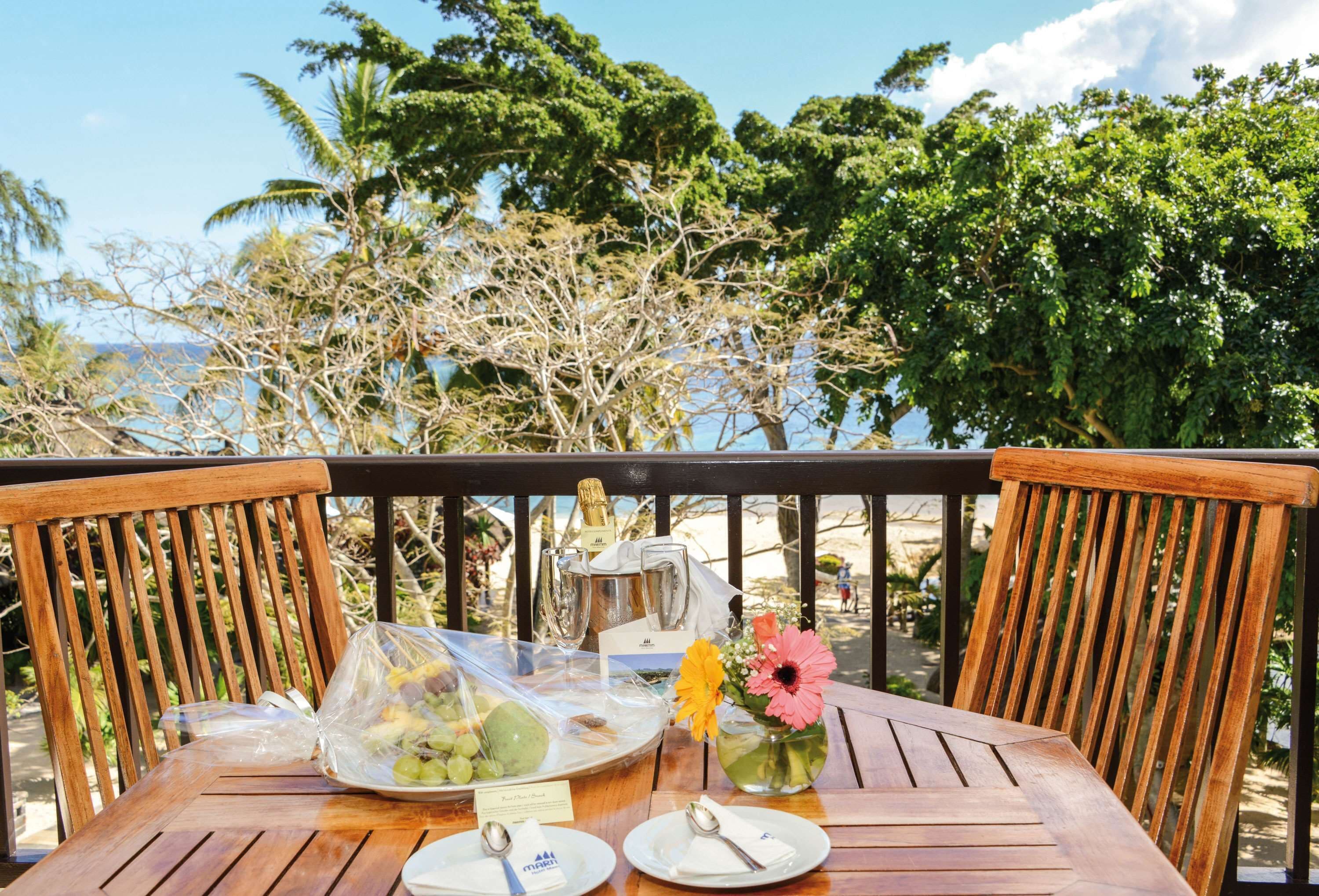 Uma mesa de madeira com uma garrafa de champanhe, um jarro de vidro e um vaso com flores.