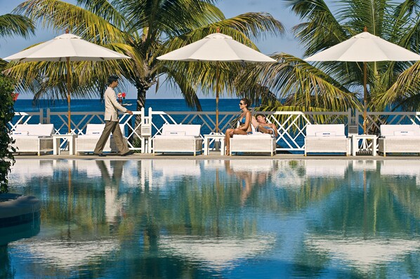 Una piscina al aire libre, una piscina con borde infinito, sombrillas