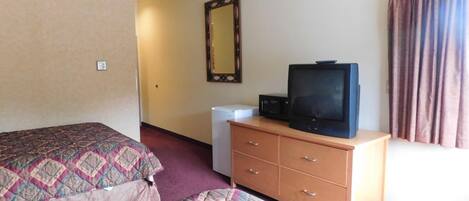 Ein Hotelzimmer mit Bett, Schminktisch, Fernseher und Spiegel.