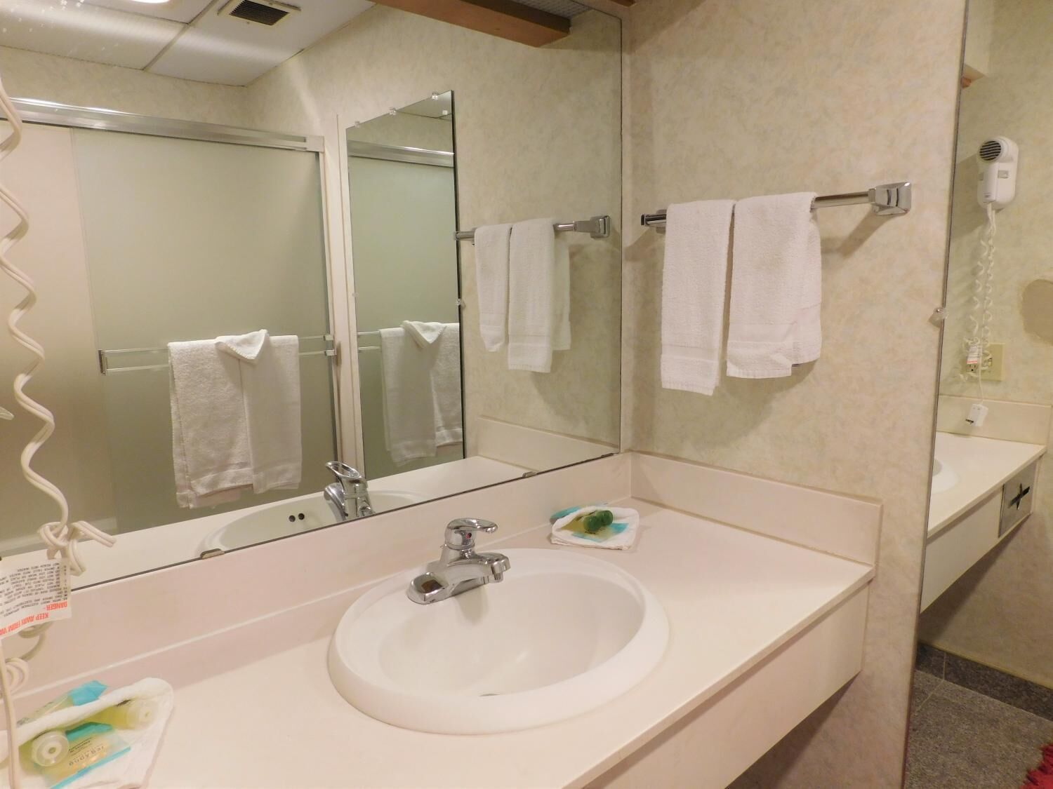 A bathroom with a white sink, a mirror, and a towel rack with white towels.
