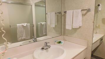 A bathroom with a white sink, a mirror, and a towel rack with white towels.