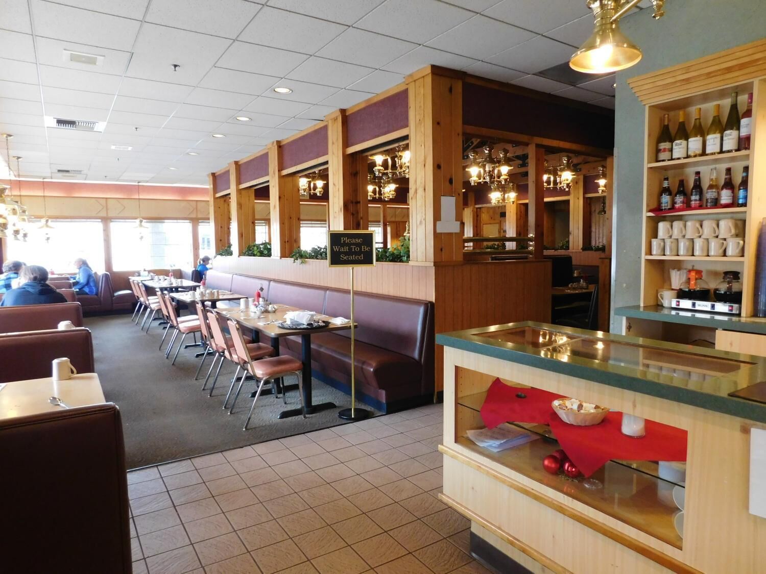 A restaurant with booths and tables, a bar area, and a counter with a red cloth.