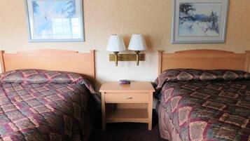 A hotel room with two beds, a nightstand, and two wall-mounted lamps.