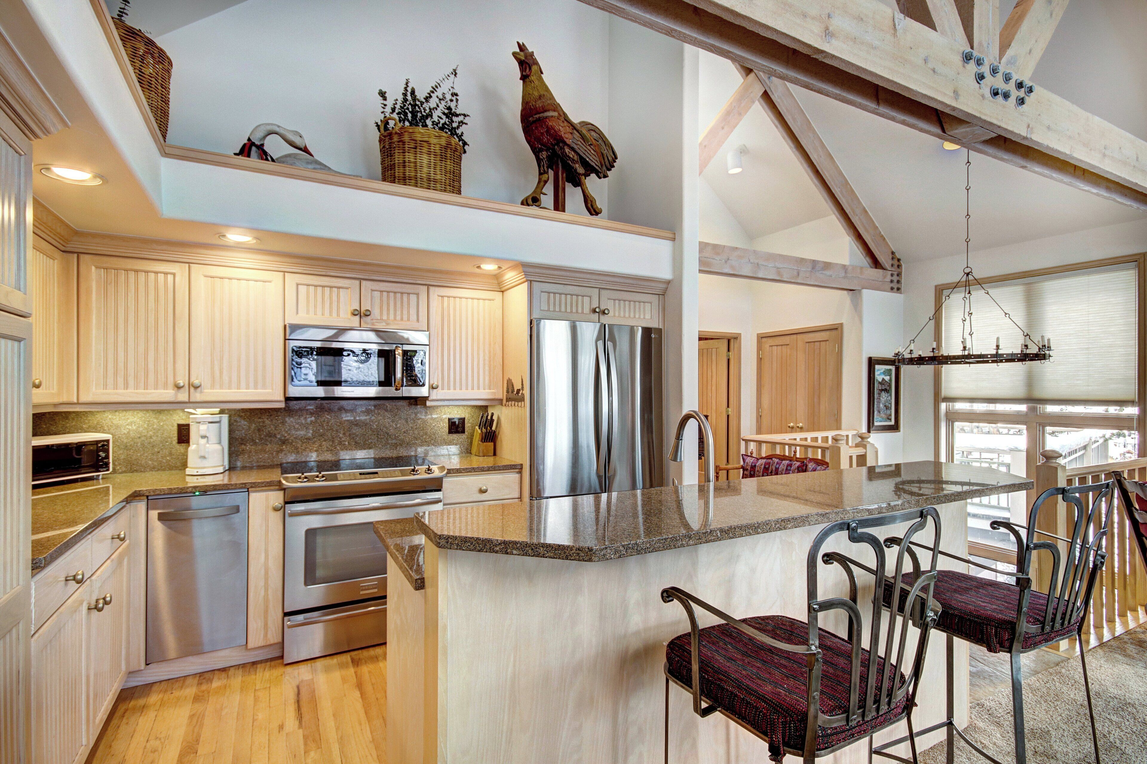 A modern kitchen with stainless steel appliances, wooden cabinets, and a central island with bar stools.