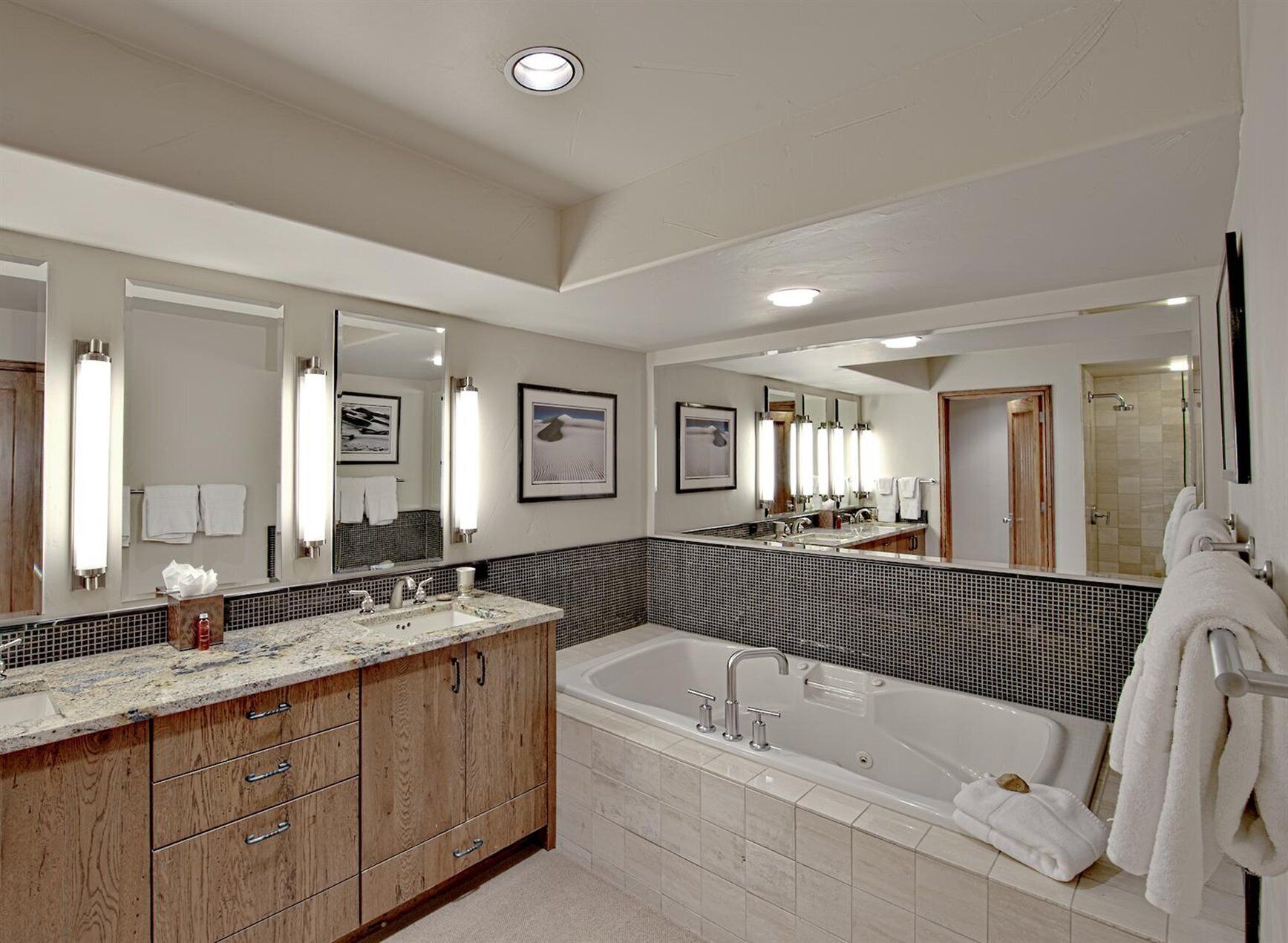 A modern bathroom with a large bathtub, a double sink vanity, and multiple mirrors.
