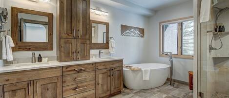 Un baño moderno con tocador de madera, una bañera independiente y cabina de ducha con paredes de vidrio.