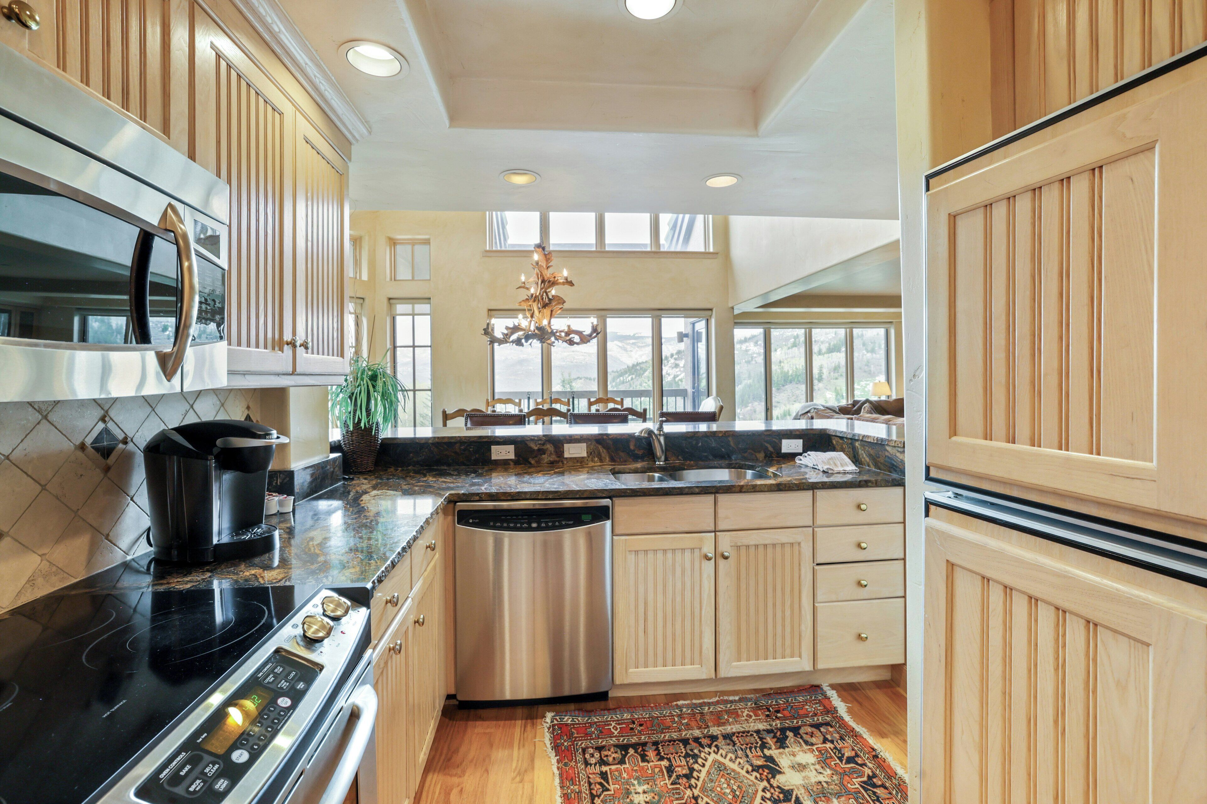 A modern kitchen with a stainless steel stove, dishwasher, and a large island with a sink.