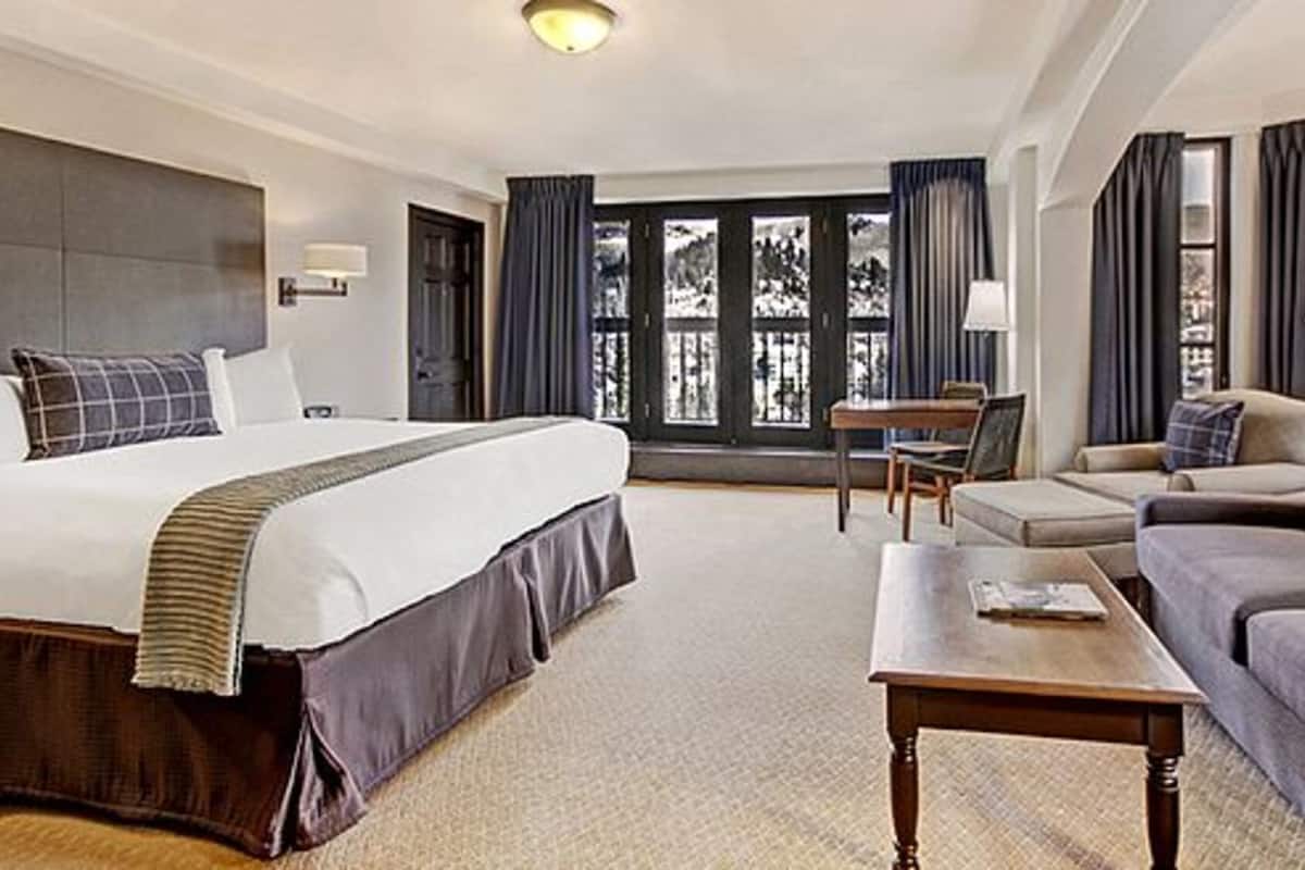 Una habitación de hotel con cama, sofá, mesa de centro y escritorio.
