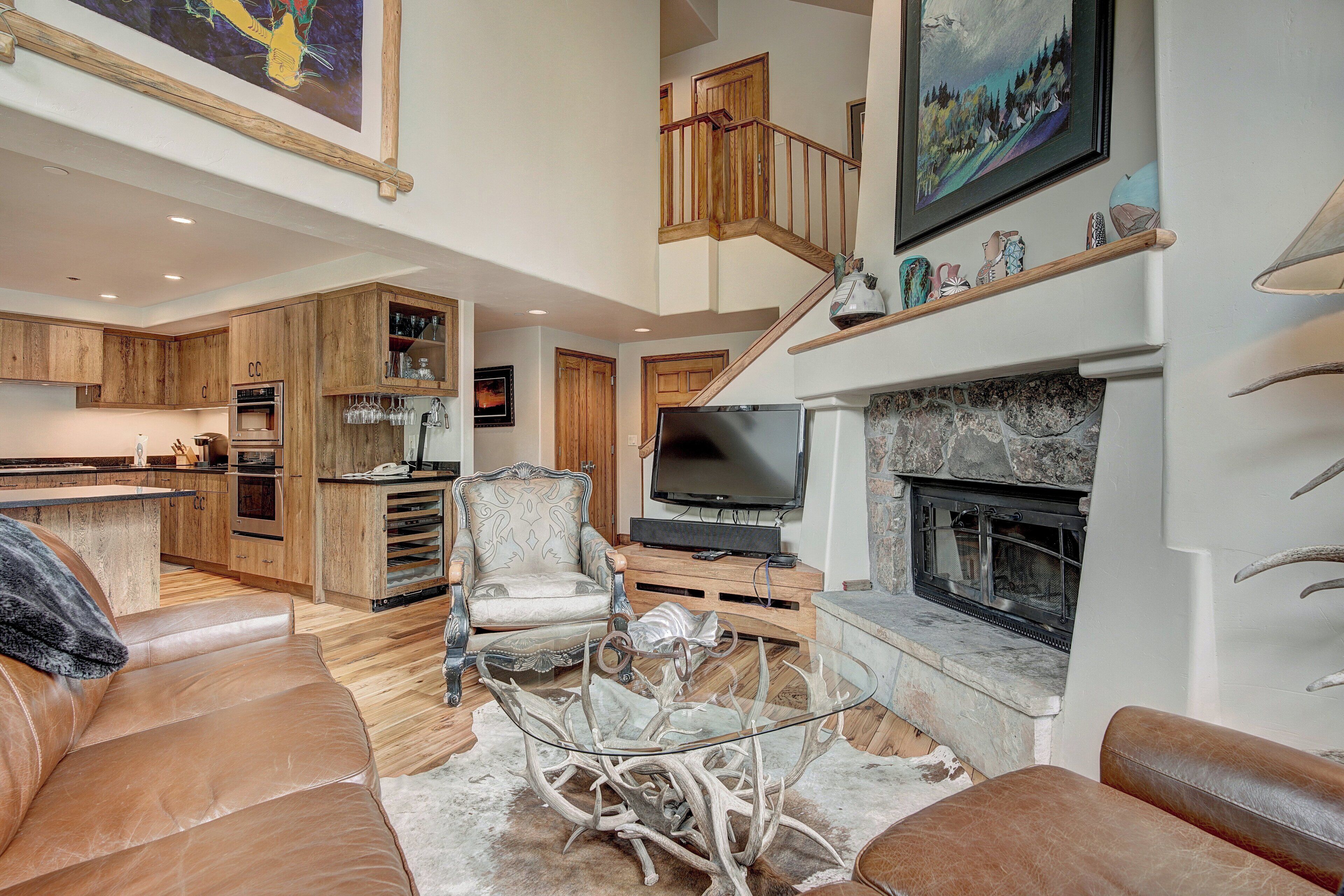 A spacious living area with a fireplace, leather sofas, and a glass coffee table.