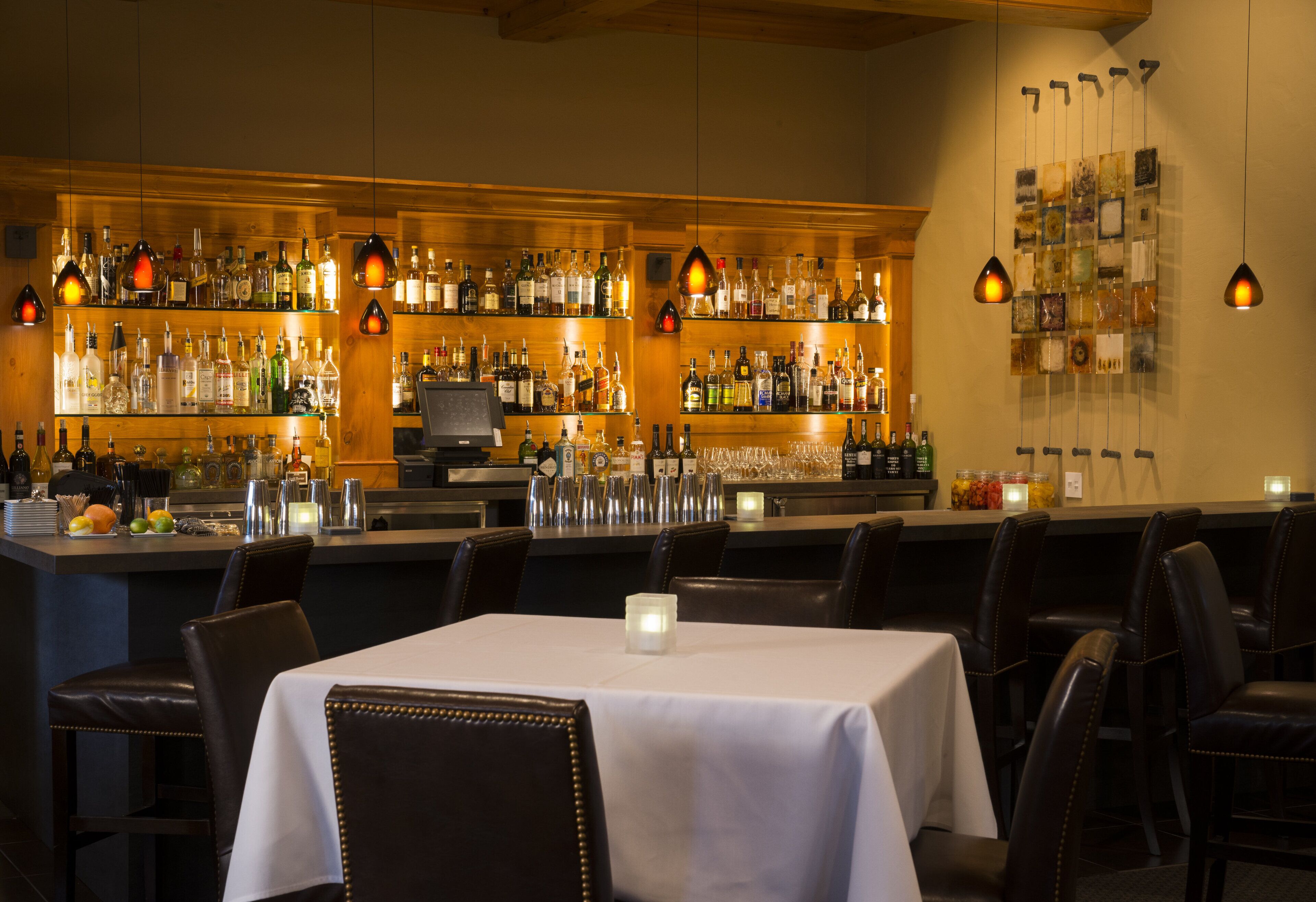 A bar area with multiple shelves of bottles, a counter, and bar stools.