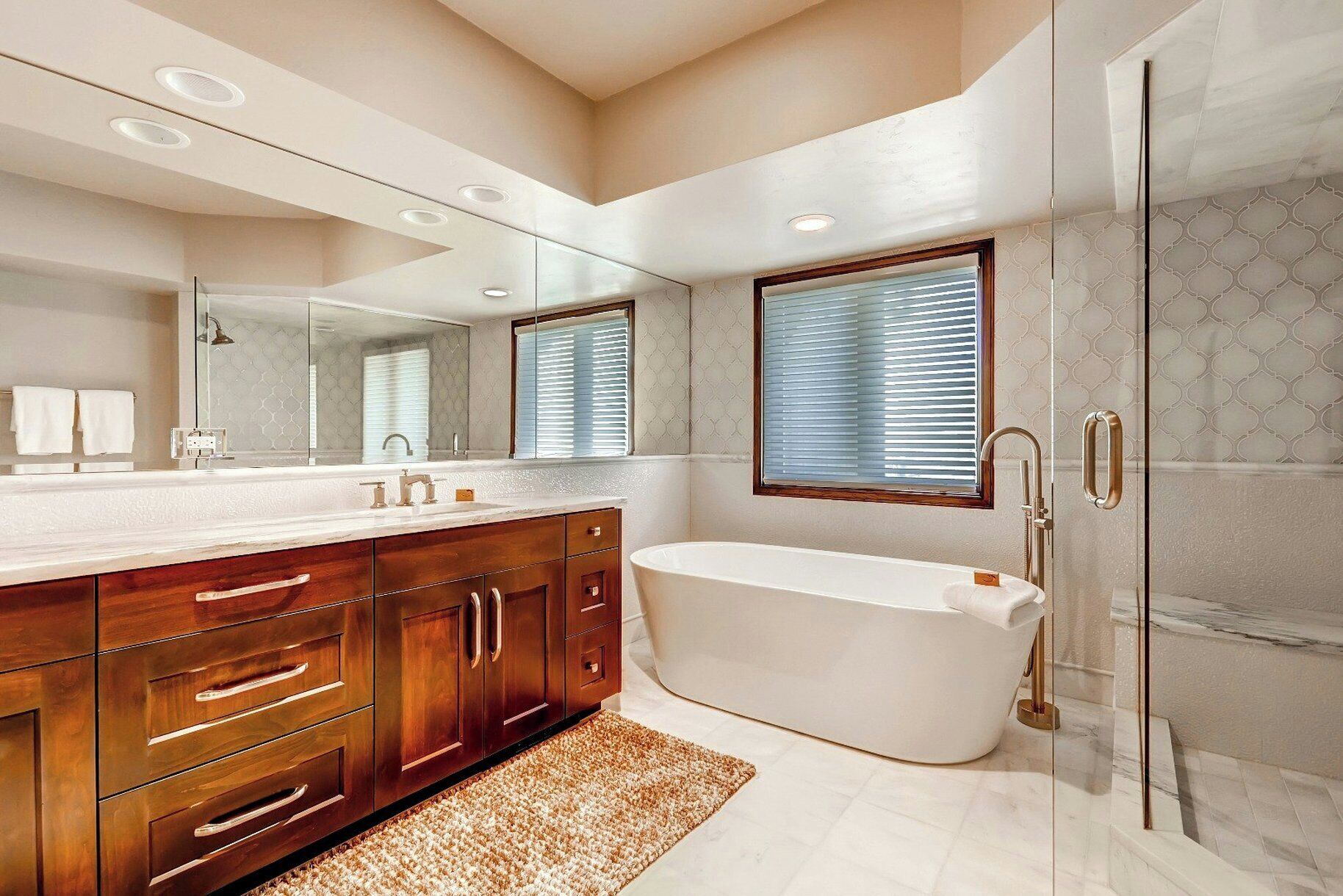 A modern bathroom with a large vanity, a freestanding bathtub, and a glass-enclosed shower.