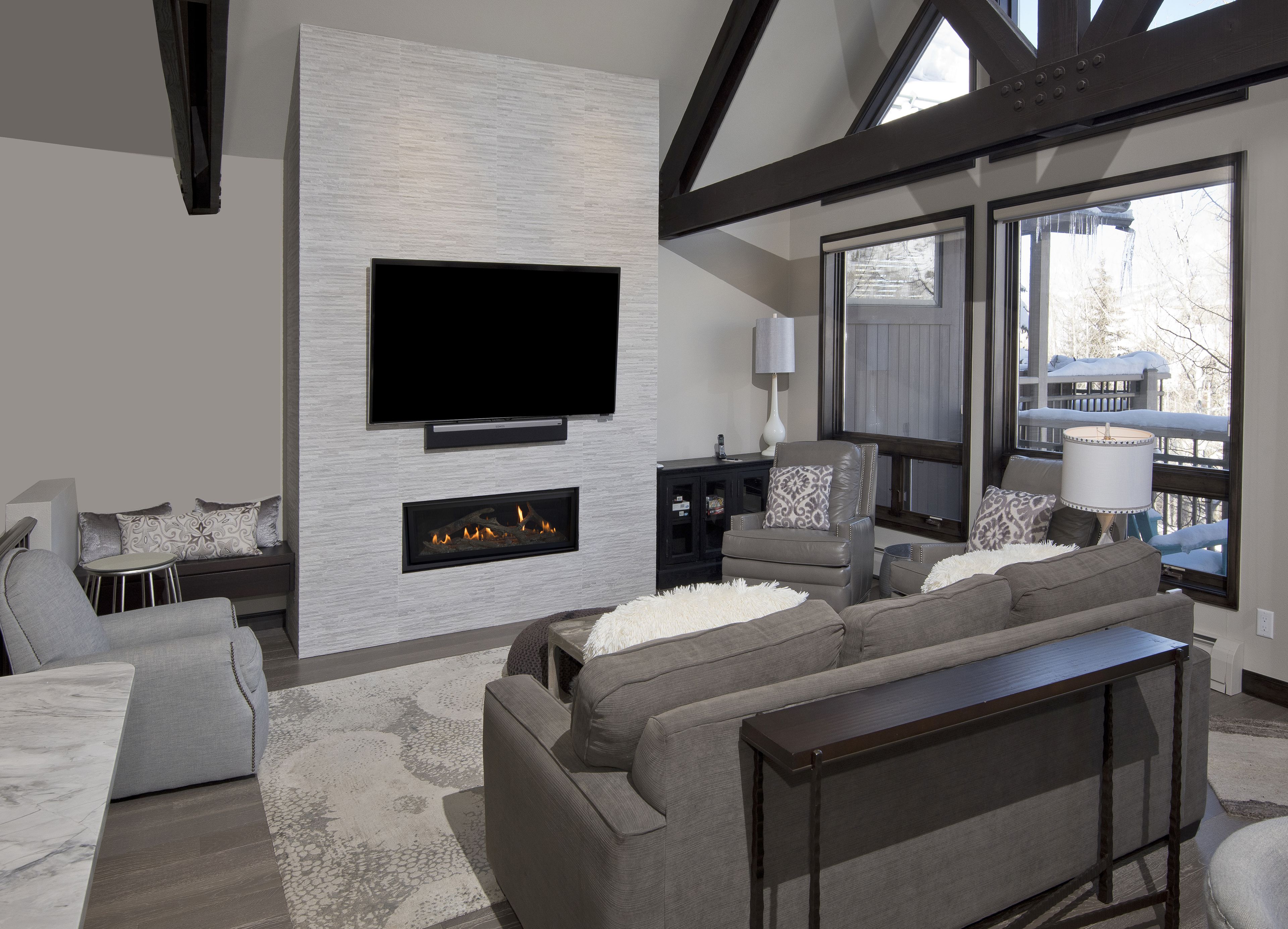 Een moderne woonkamer met een open haard, een flatscreen televisie en een comfortabele zithoek.