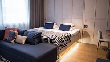 Ett modernt hotellrum med en soffa, två sängar, ett sängbord och en stol.