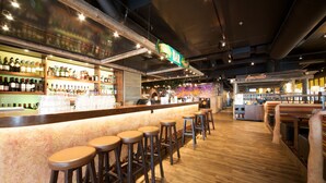 Un bar con sgabelli di legno e una varietà di bottiglie sugli scaffali.