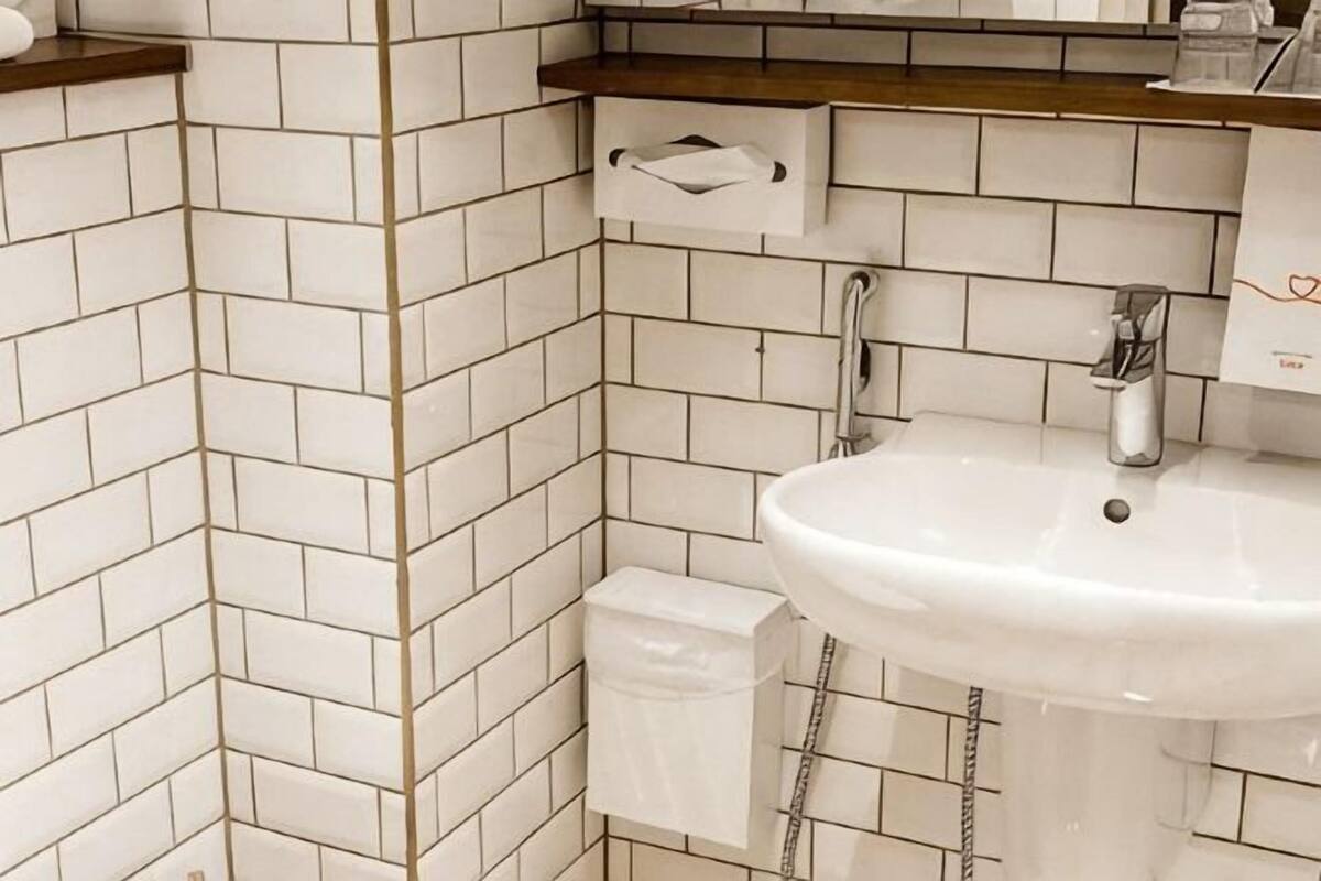 A bathroom with white tiled walls, a sink, a mirror, and a towel rack.