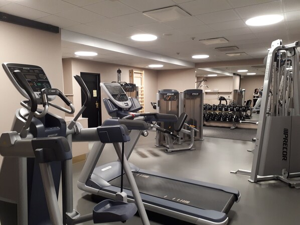 A gym with treadmills, weight machines, and dumbbells.