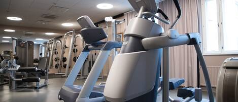 Un gimnasio con máquinas de ejercicio, incluyendo cintas de correr y elípticas, además de una zona de levantamiento de pesas.