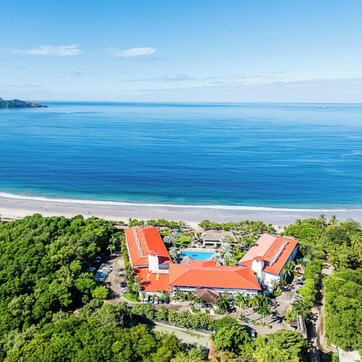 An aerial view of a resort with multiple buildings, a beach, and a large body of water.