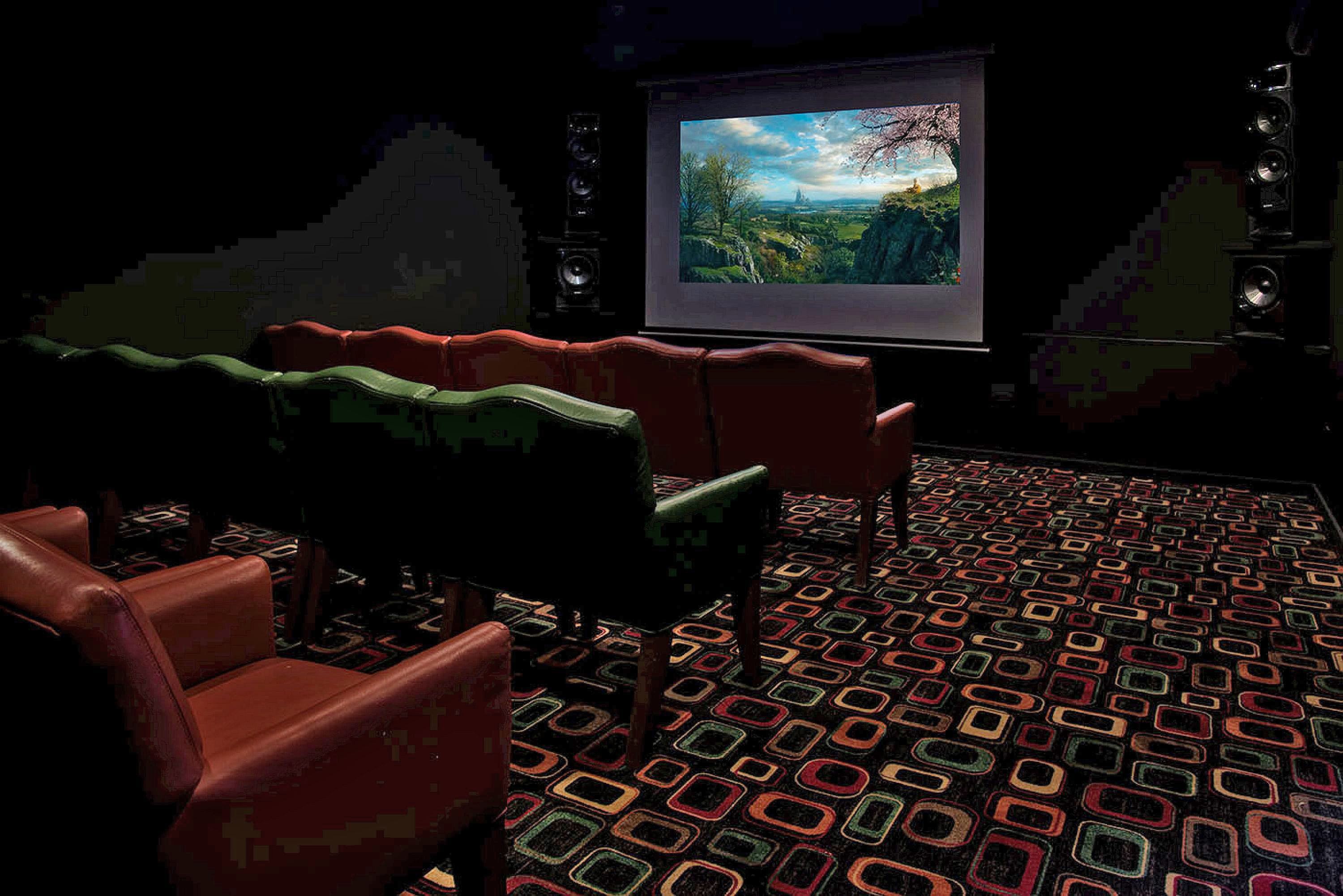 A theater with red seats and a patterned carpet.