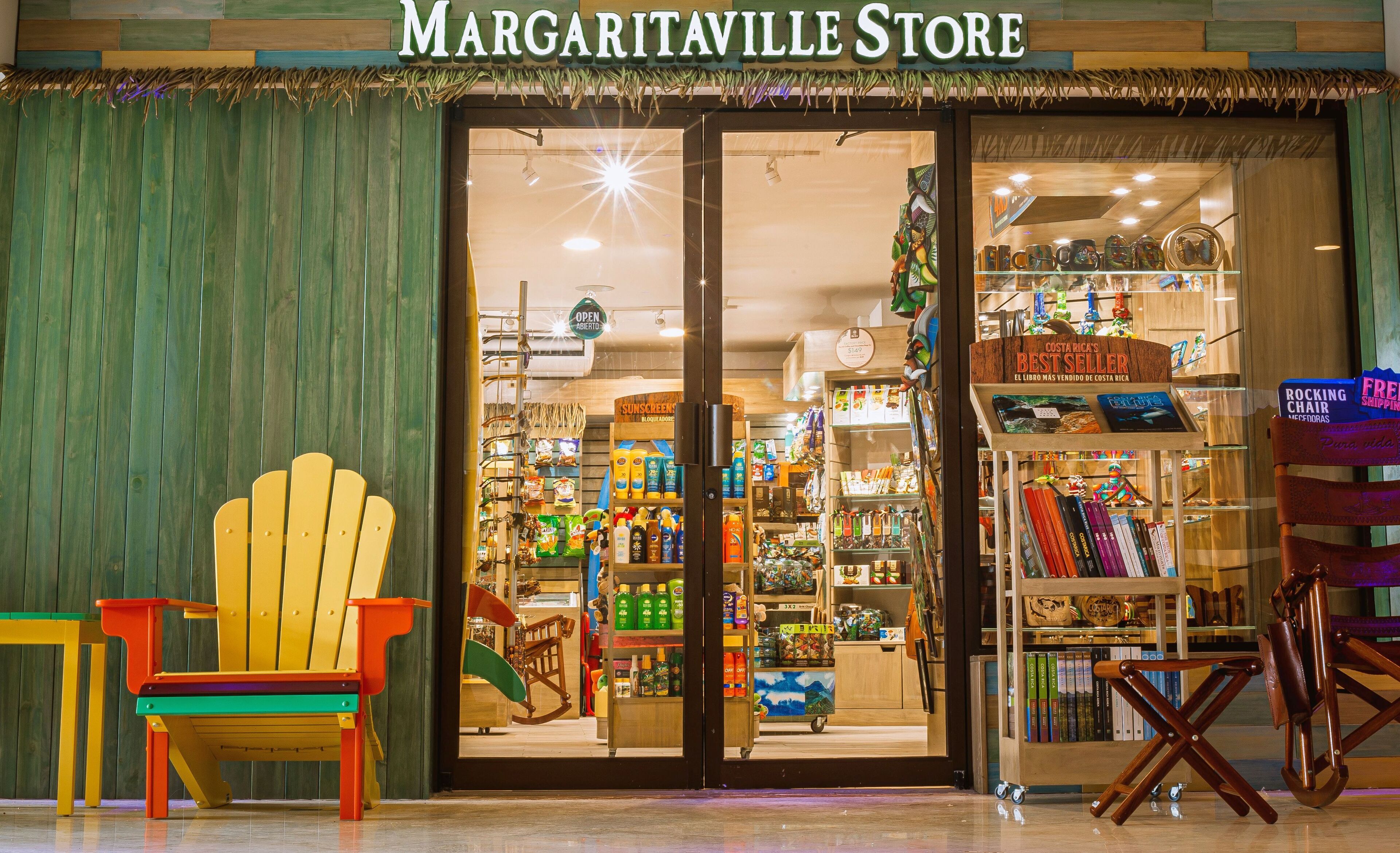 Het uiterlijk van de Margaritaville Store met een kleurrijke stoel ervoor en een presentatie van boeken en souvenirs binnen.