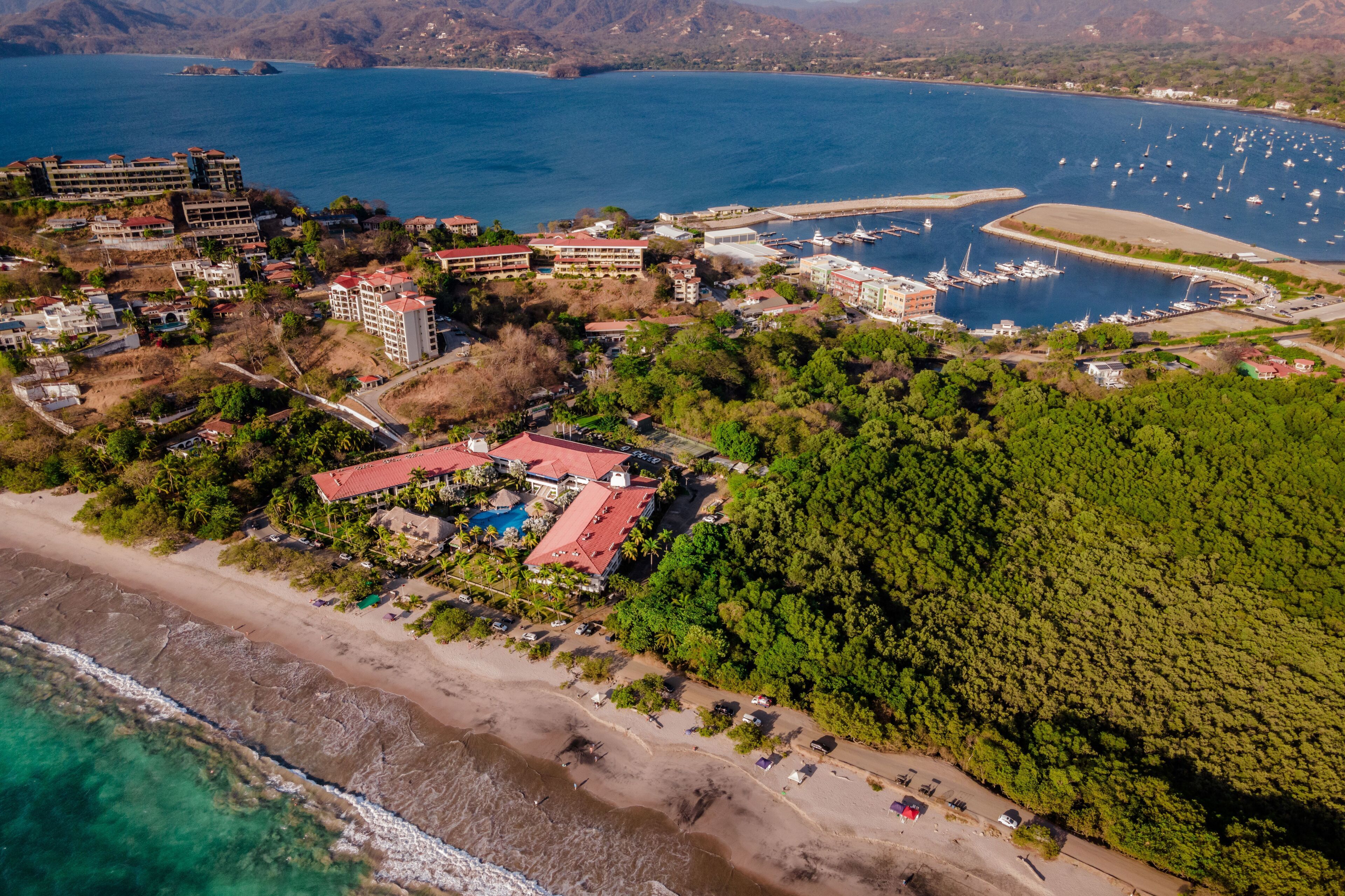 An aerial view of a coastal resort with multiple buildings, a marina, and a beach.