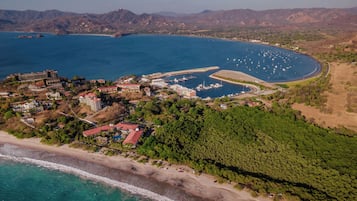 Vue aérienne d’une zone côtière avec un port de plaisance, des bâtiments et une plage.