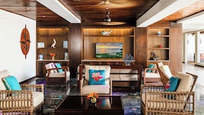 A spacious lobby with wooden paneling, a large painting, and wicker furniture.
