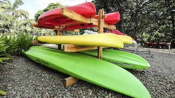 A stack of kayaks on a wooden stand with pebbles around.
