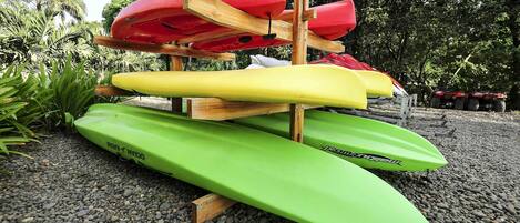 A stack of kayaks on a wooden stand with pebbles around.