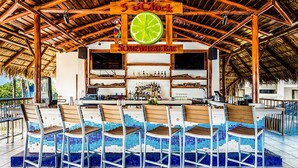 A bar area with a wooden ceiling and a sign reading "5 oClock Somewhere Bar".