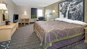 A hotel room with a large bed, a desk with a television, a chair, a desk lamp, and a large framed picture on the wall. - Super 8 by Wyndham Fort Collins (Fort Collins)