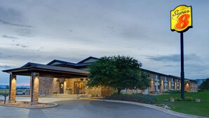 A hotel with a Super 8 sign, brick exterior, covered entrance, and a well-maintained lawn. - Super 8 by Wyndham Fort Collins (Fort Collins)