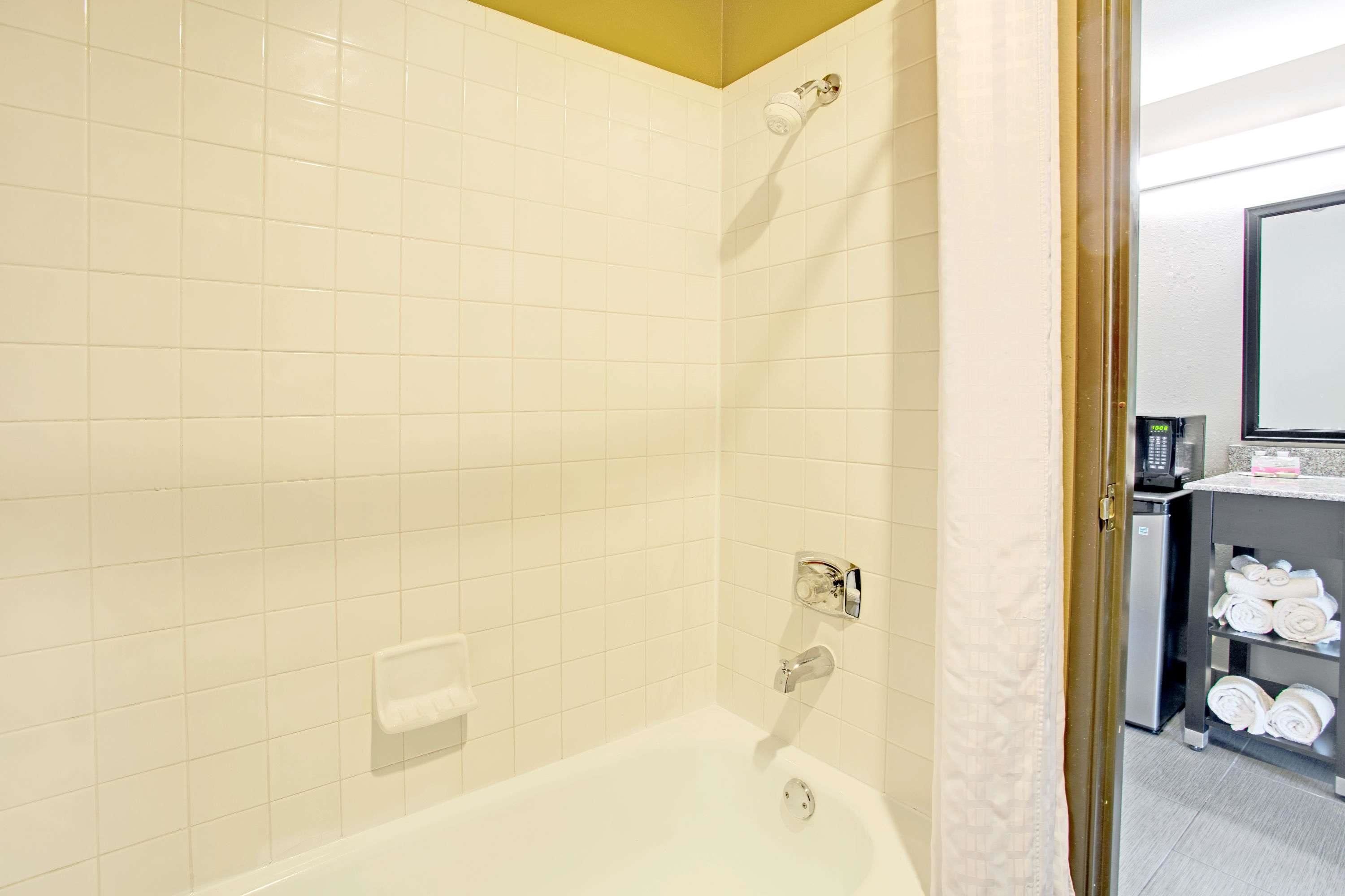 A bathroom with a white bathtub, a showerhead, and a towel rack.