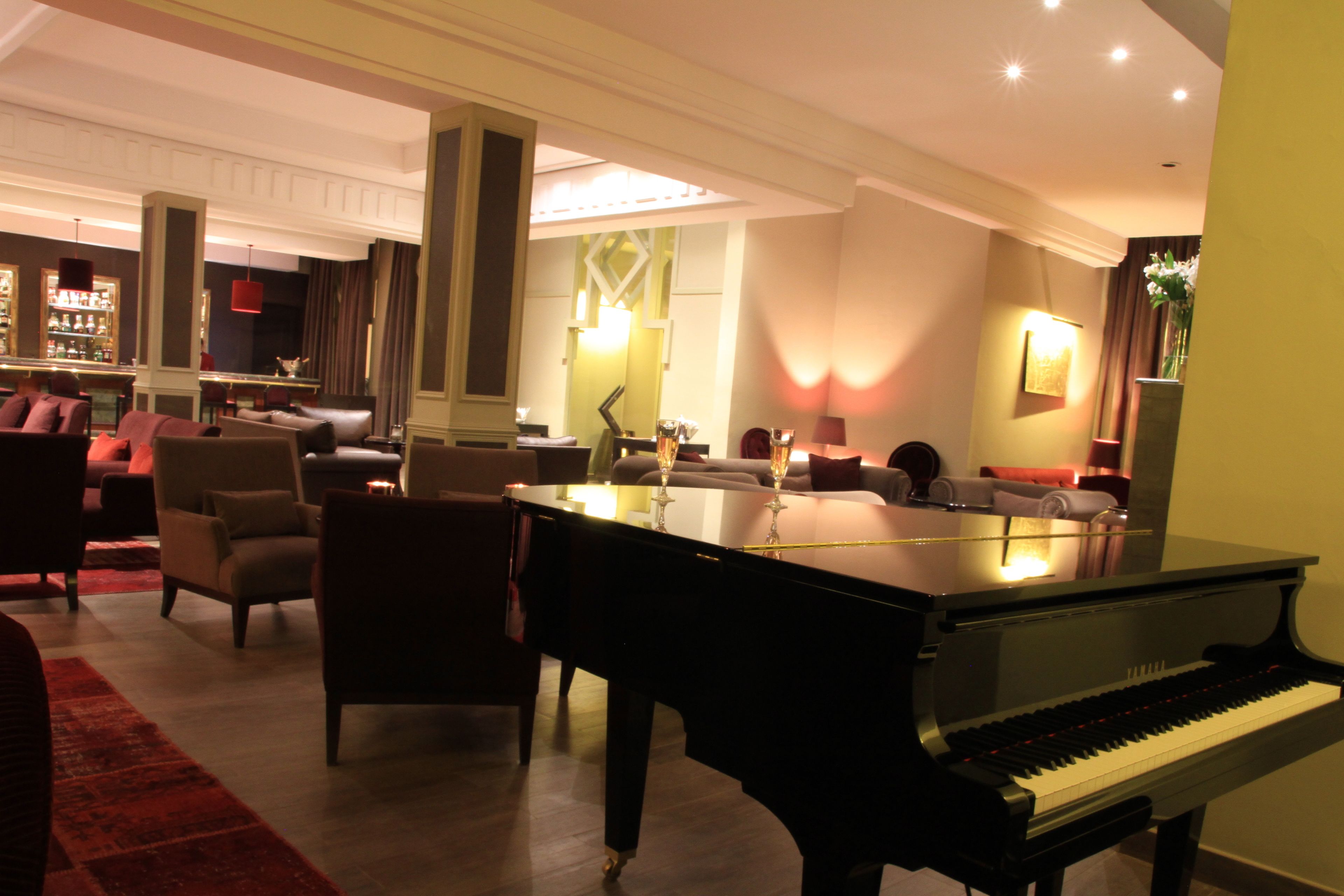 Un vaste espace de vie agrémenté d’un magnifique piano à queue, de sièges confortables et d’un bar situé au fond de la pièce.