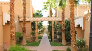 A pathway flanked by palm trees and a building with a patterned facade. - Le Berbere Palace (Ouarzazate)