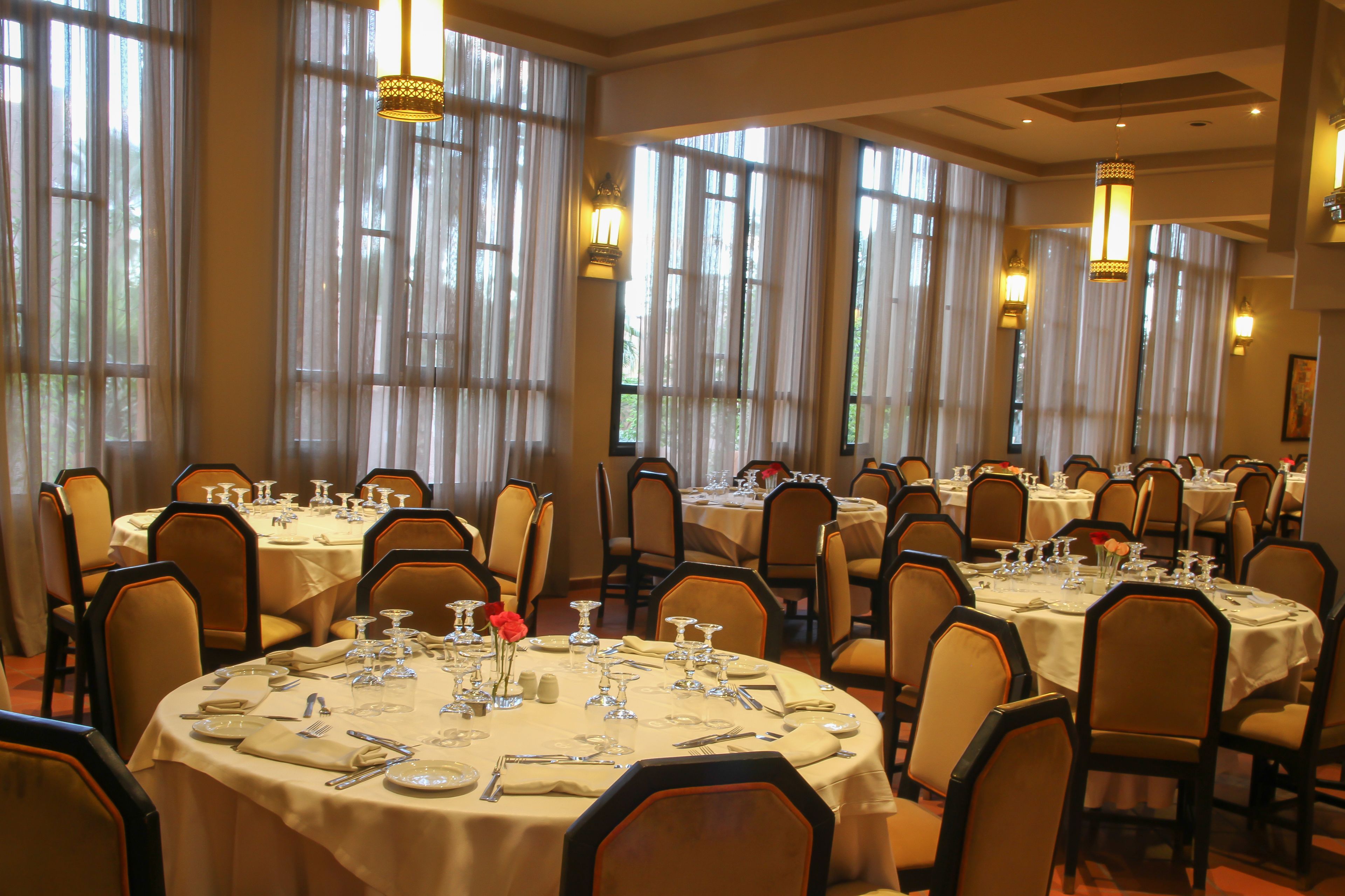 A banquet hall with multiple round tables set for dining, each with chairs and table settings.