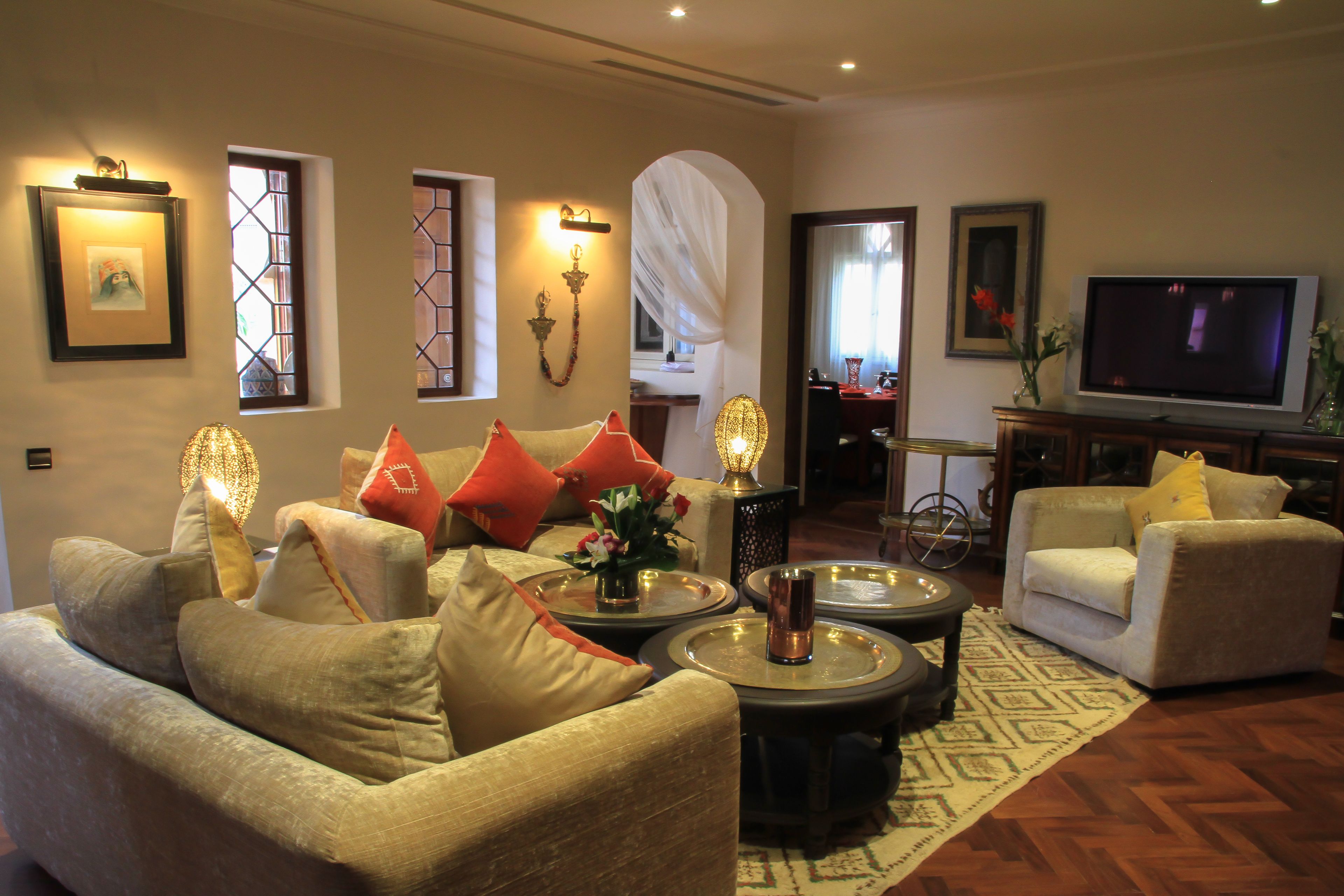 A living room with a sofa, coffee table, and TV. There are decorative lights and a vase with flowers.