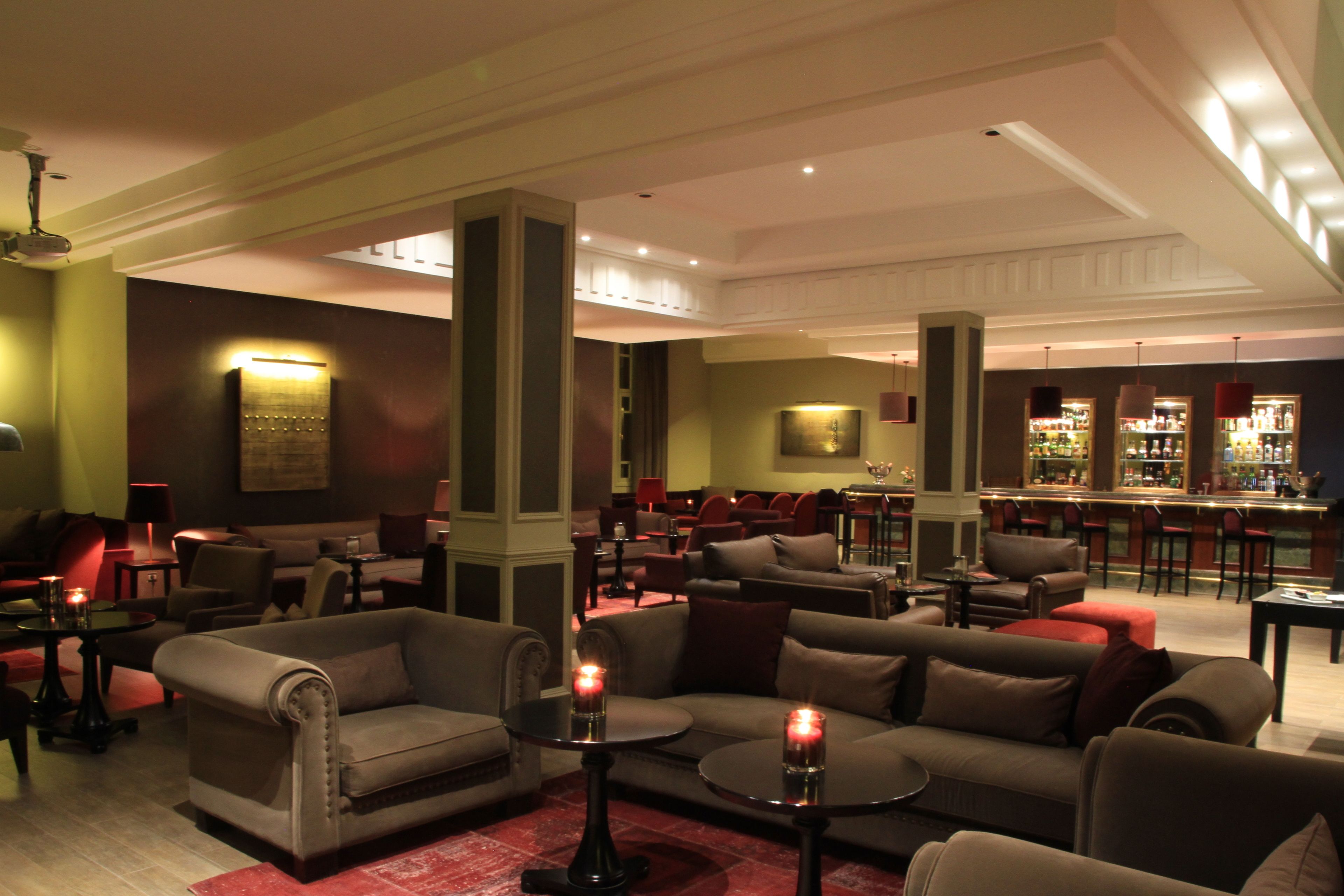 Een ruime lobby met meerdere zithoeken, inclusief banken en stoelen, en een bar met een goed gevulde drankendisplay.