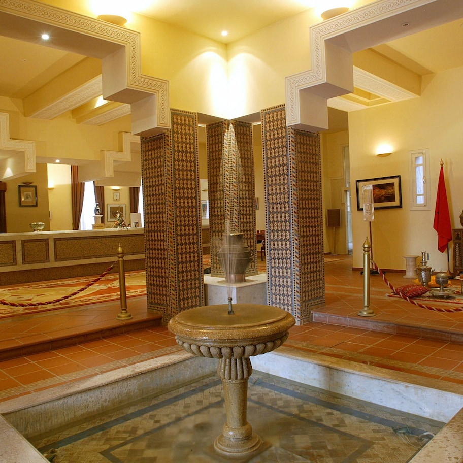 A lobby with a central fountain, patterned curtains, and a reception desk.
