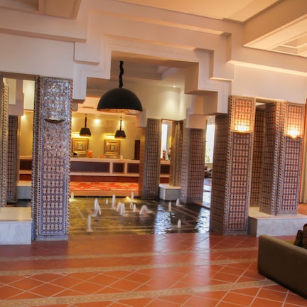 A lobby with patterned pillars, a water feature, and a seating area.