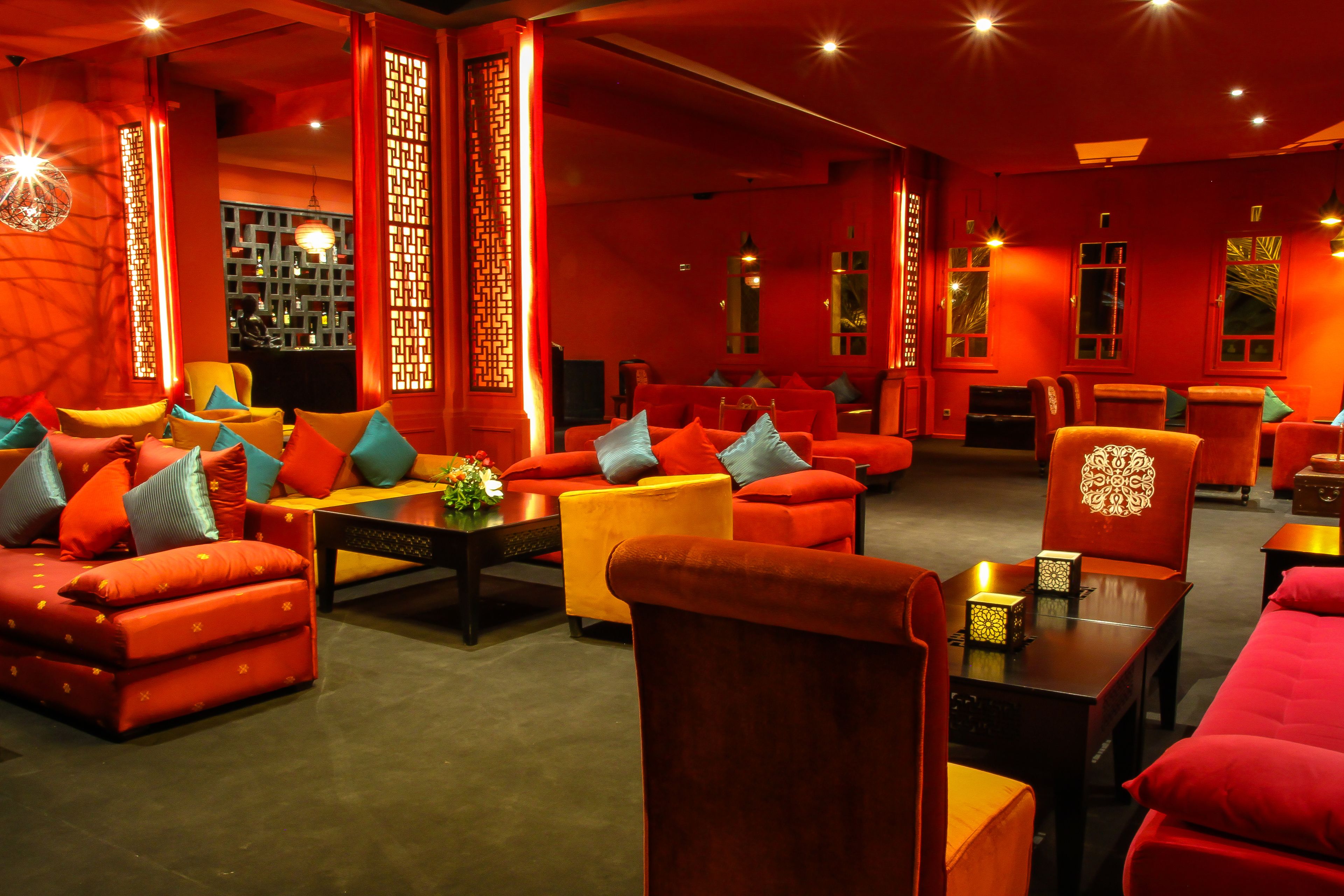 Una habitación con sofás y sillones rojos, una mesa de centro e iluminación decorativa.