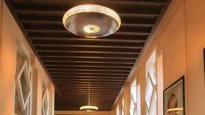 A hallway with patterned rugs, pendant lights, and a framed picture on the wall. - Le Berbere Palace (Ouarzazate)
