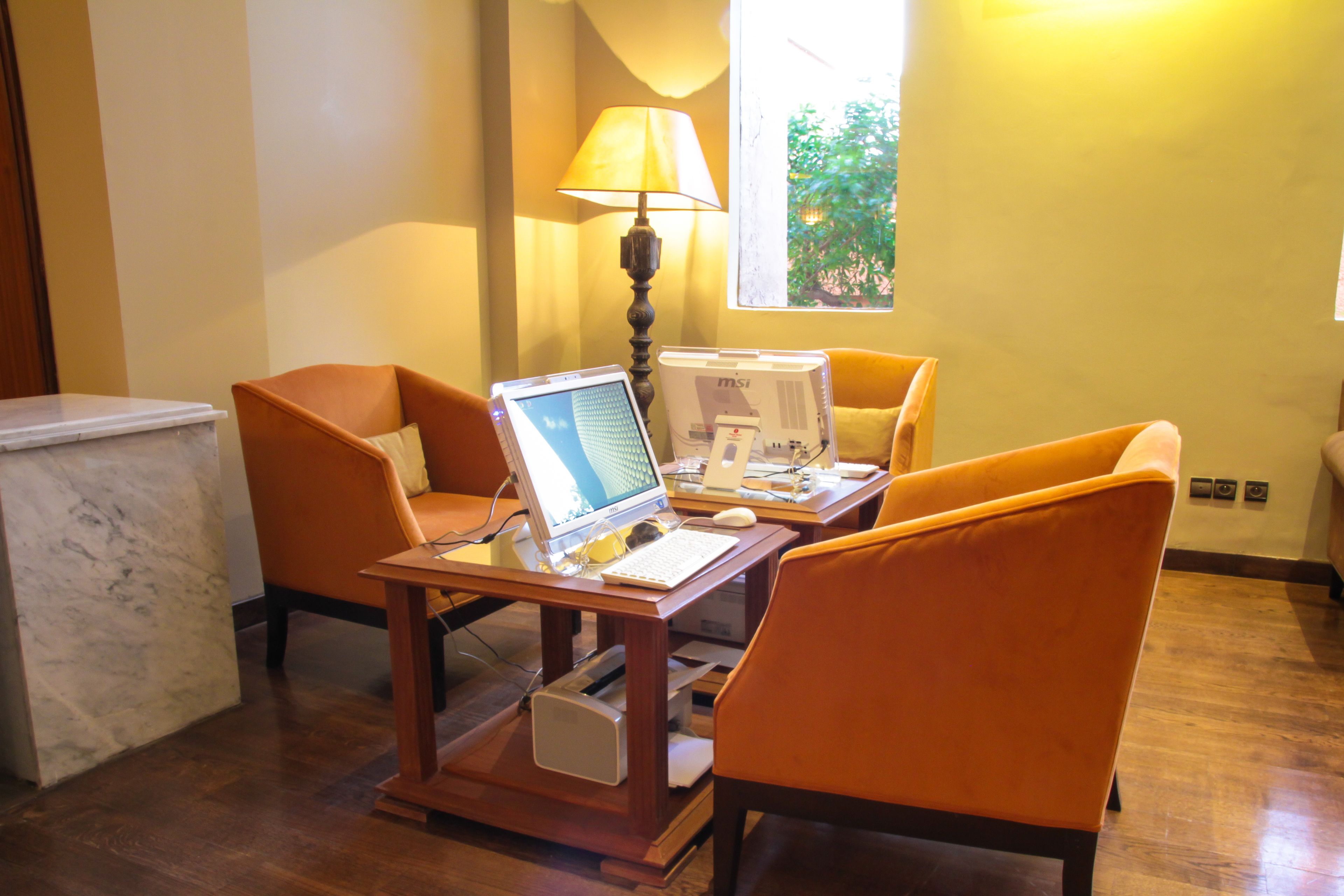 A workspace with a desk, two chairs, a laptop, a desktop computer, and a lamp.