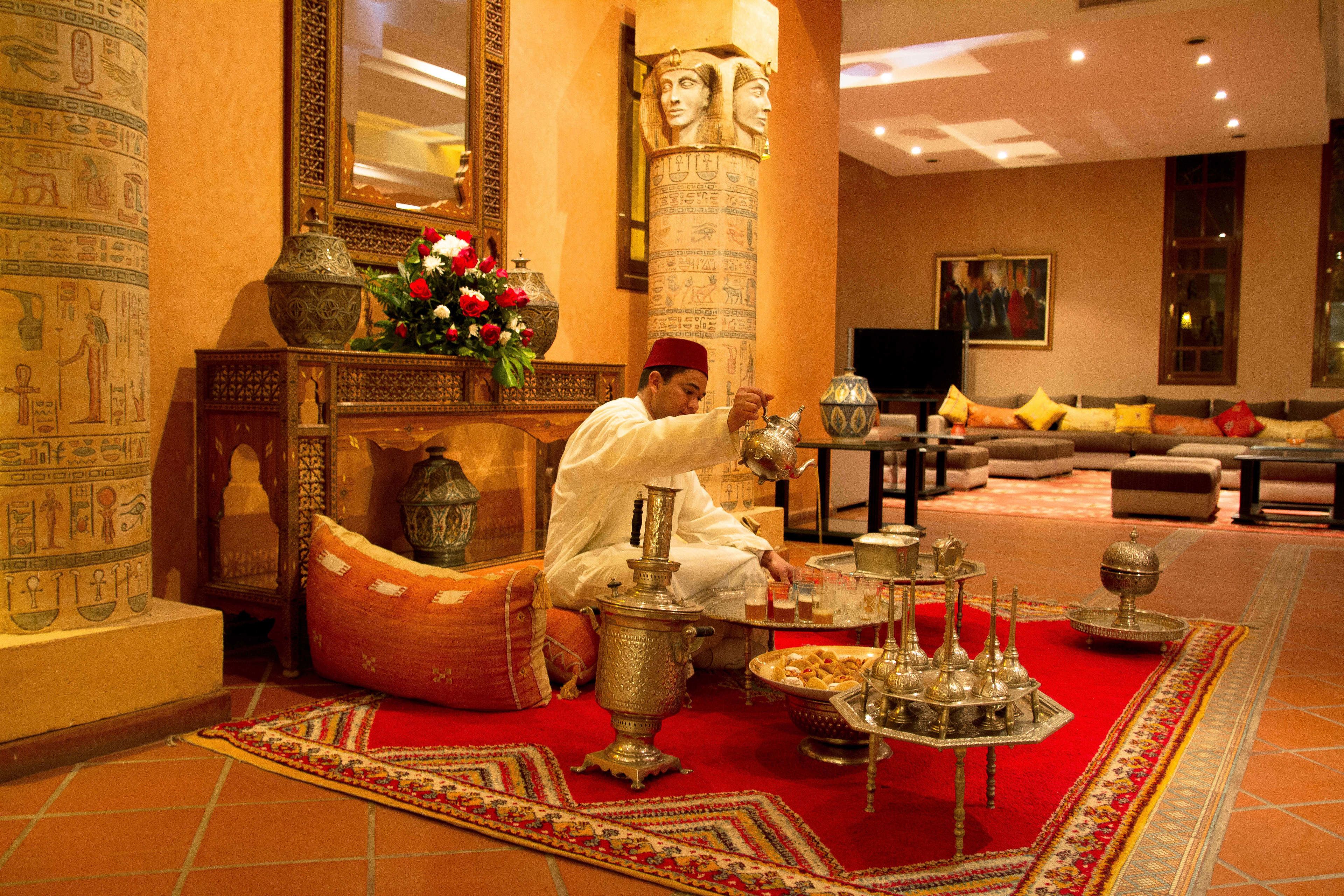 Un intérieur de style traditionnel, agrémenté d’une grande colonne décorative, d’un ensemble de canapés et d’une table basse ornée d’objets en métal ouvragé.